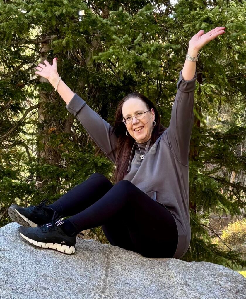 Midlife woman sitting on top of a rock living her best life.