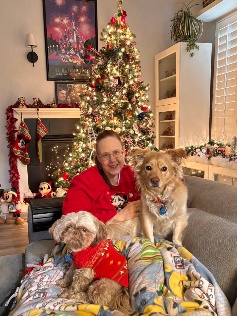 Two dogs and happy woman smiling next to the Christmas tree. 