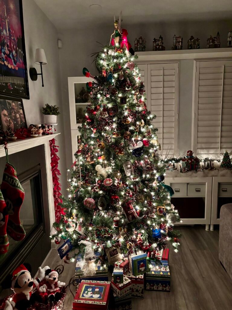 Cozy living room Christmas tree covered in meaningful family ornaments, glowing with white lights and surrounded by holiday decor and wrapped keepsake boxes
