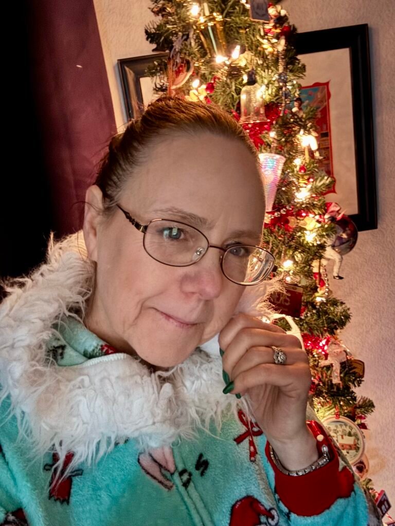Woman standing in front of the Christmas tree in her winter pajamas