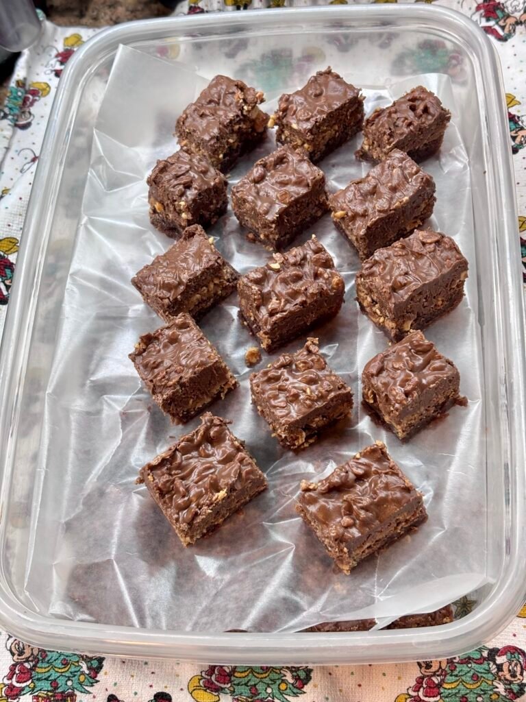 Peanut butter crack brownies stacked in a container with wax paper between layers
