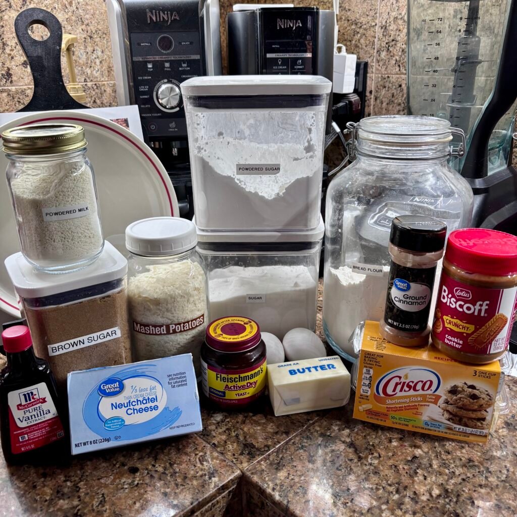 Ingredients for homemade cookie butter cinnamon rolls laid out on a kitchen counter
