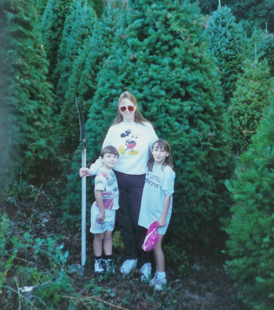 Mom and kids in the mountains cutting down a Christmas tree